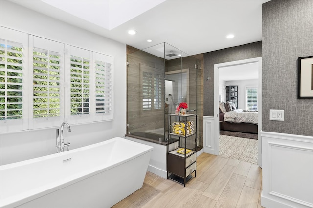 ensuite bathroom featuring a wainscoted wall, a freestanding bath, ensuite bathroom, a stall shower, and wood finished floors