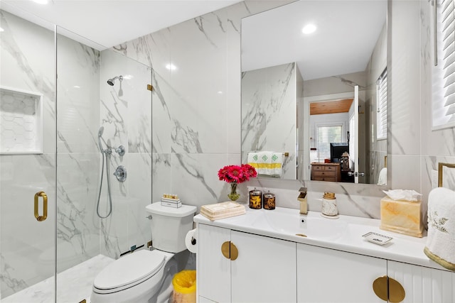 bathroom featuring toilet, tile walls, a marble finish shower, and vanity