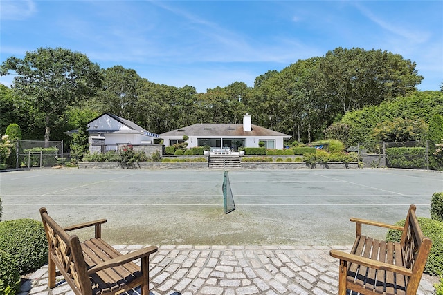 exterior space featuring a tennis court and fence