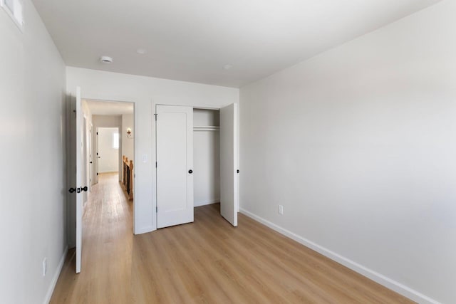 unfurnished bedroom with light wood-style floors, a closet, and baseboards