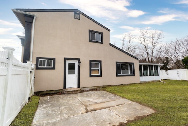 back of house featuring a fenced backyard, a sunroom, a yard, stucco siding, and a patio area