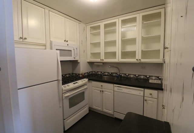 kitchen with white cabinetry, white appliances, dark countertops, and a sink