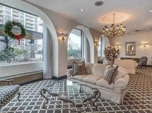 interior space featuring baseboards, arched walkways, a textured ceiling, and a notable chandelier