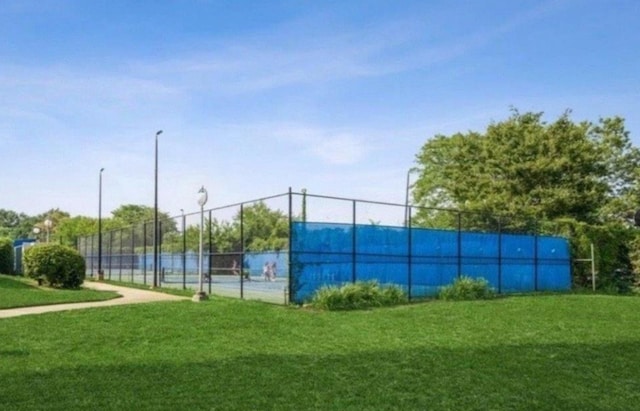 view of sport court with a yard and fence