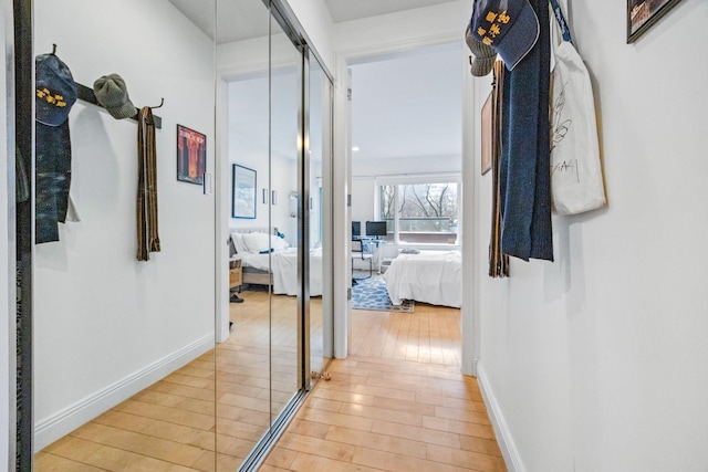 corridor with light wood-type flooring and baseboards