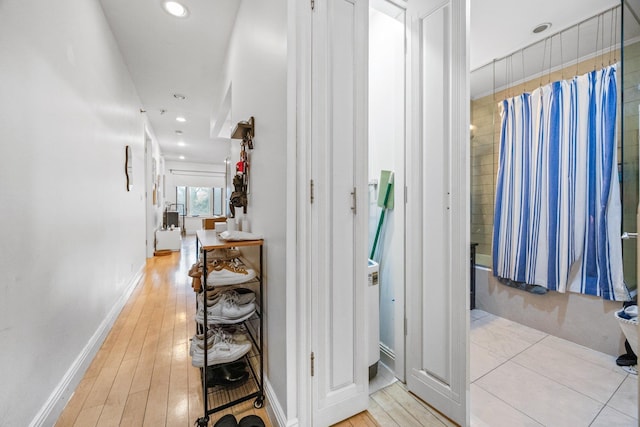 corridor with baseboards, recessed lighting, and light wood-style floors