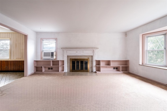 unfurnished living room featuring carpet, a premium fireplace, plenty of natural light, and baseboards