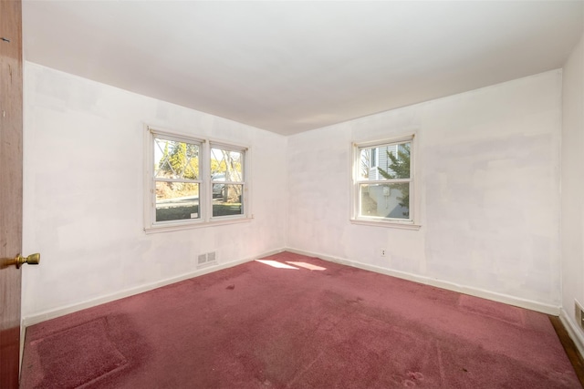 carpeted empty room with plenty of natural light, visible vents, and baseboards