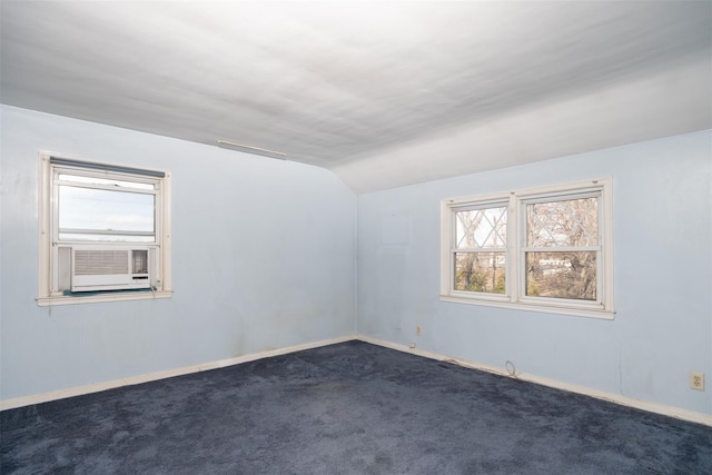 empty room featuring lofted ceiling, dark colored carpet, cooling unit, and baseboards