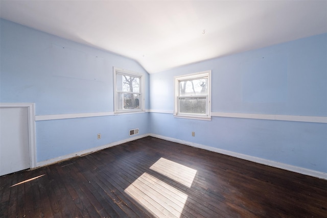 unfurnished room with vaulted ceiling, wood-type flooring, visible vents, and baseboards