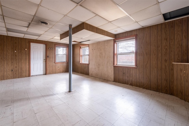 basement with visible vents, wood walls, a drop ceiling, and tile patterned floors