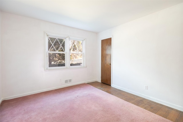 unfurnished room with wood finished floors, visible vents, and baseboards