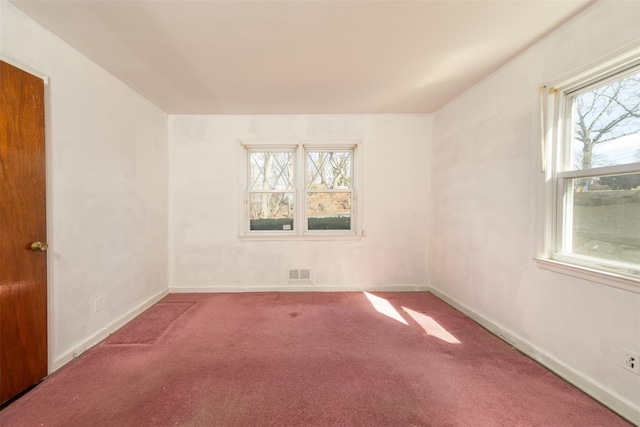 carpeted spare room featuring visible vents and baseboards