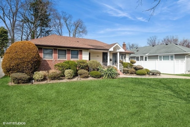 ranch-style house with brick siding, a chimney, a front yard, and fence