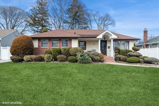 ranch-style house featuring brick siding, fence, and a front yard