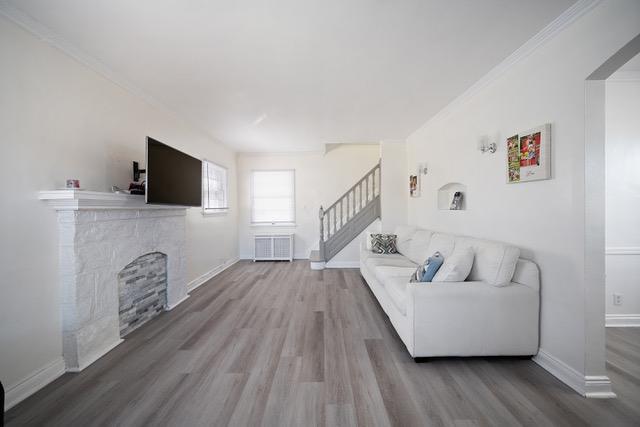 living area with stairway, wood finished floors, and baseboards