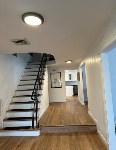 staircase featuring baseboards, visible vents, and wood finished floors