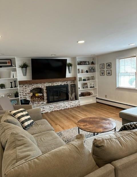 living room featuring a baseboard heating unit, a brick fireplace, wood finished floors, and recessed lighting