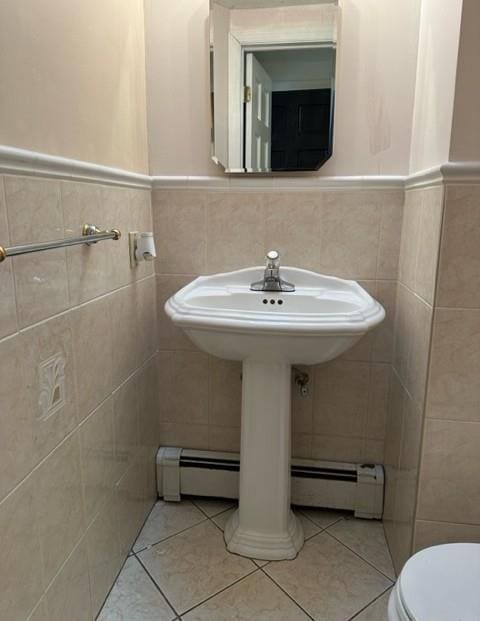 half bath with tile patterned flooring, wainscoting, and tile walls