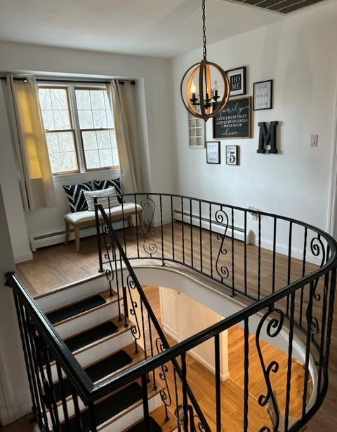 stairs with a notable chandelier and wood finished floors