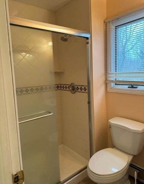 bathroom with toilet, a stall shower, and a baseboard heating unit