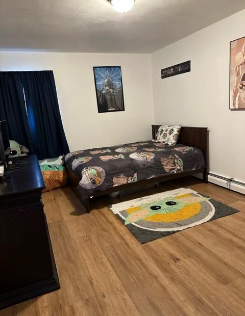 bedroom with baseboard heating and wood finished floors