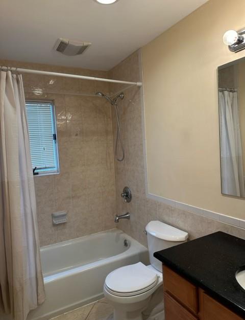 bathroom with tile walls, visible vents, shower / bathtub combination with curtain, and vanity