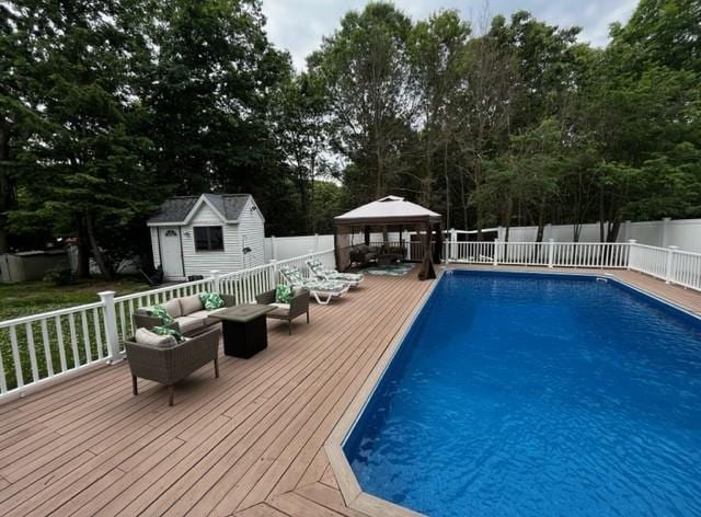 view of pool with a fenced in pool, a fenced backyard, an outdoor hangout area, a deck, and a gazebo