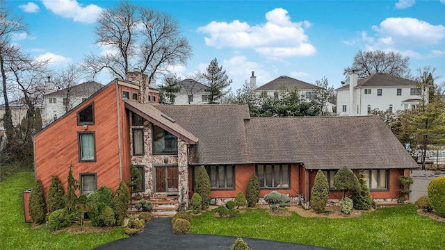 view of front of home featuring stone siding, a chimney, and a front lawn