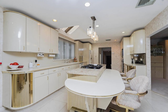 kitchen featuring visible vents, a sink, gas cooktop, light tile patterned flooring, and light countertops