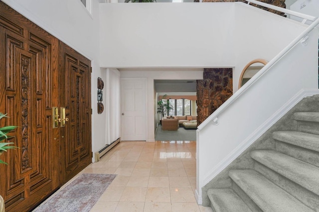 entrance foyer with stairs, a high ceiling, light tile patterned floors, and a baseboard radiator