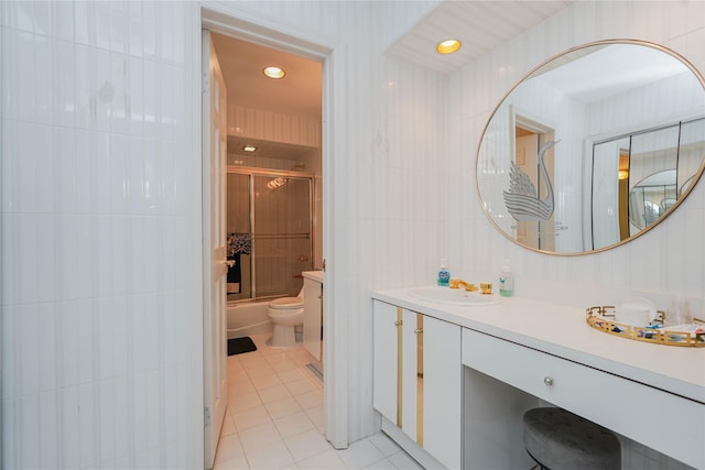 bathroom featuring vanity, enclosed tub / shower combo, tile patterned flooring, tile walls, and toilet