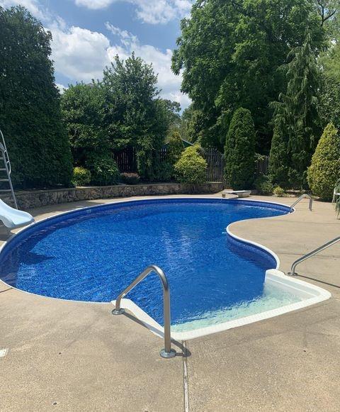 pool featuring a diving board, a patio, a water slide, and a fenced backyard