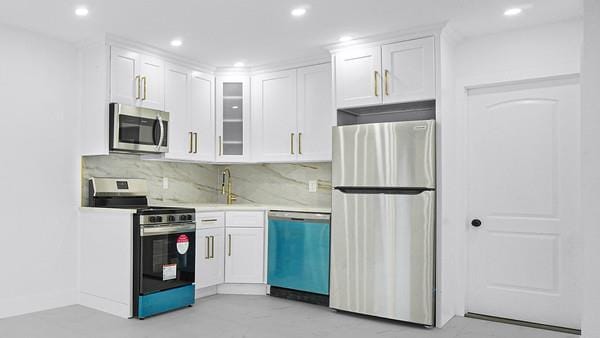 kitchen featuring appliances with stainless steel finishes, light countertops, white cabinetry, and a sink