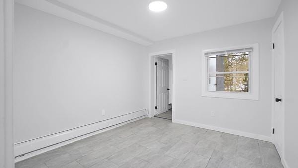 unfurnished room with baseboards and a baseboard heating unit