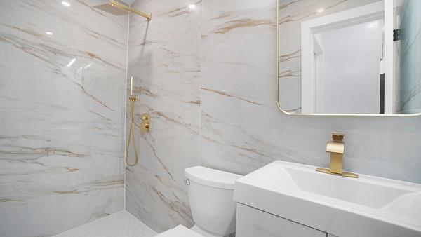 bathroom with toilet, a marble finish shower, tile walls, and vanity