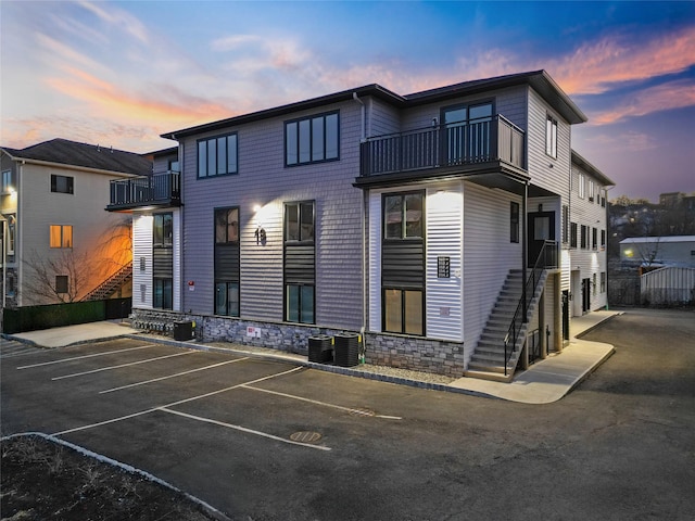 view of front of home featuring stairway, uncovered parking, and central AC