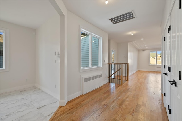 corridor with visible vents, an upstairs landing, baseboards, and radiator heating unit