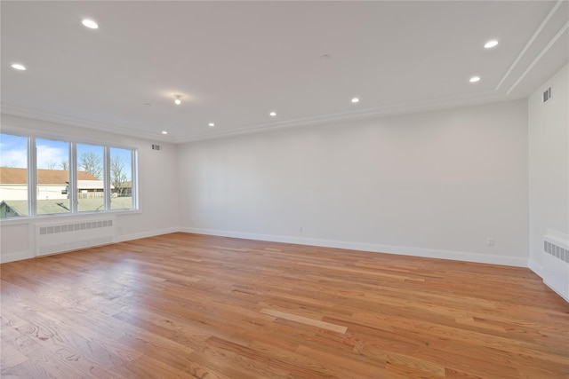 empty room with visible vents, radiator heating unit, recessed lighting, light wood-style floors, and baseboards