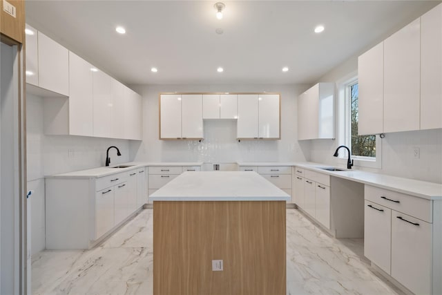 kitchen with tasteful backsplash, marble finish floor, a center island, and a sink