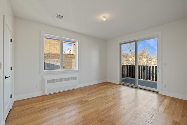 unfurnished room featuring light wood-style flooring, radiator, baseboards, and a wealth of natural light