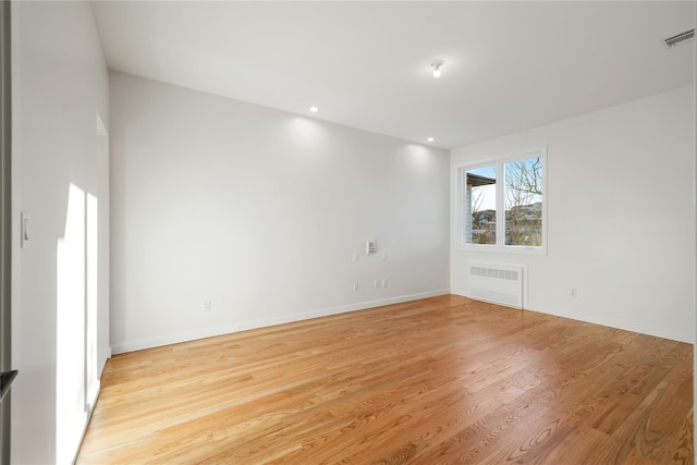 spare room with visible vents, radiator, baseboards, light wood-type flooring, and recessed lighting