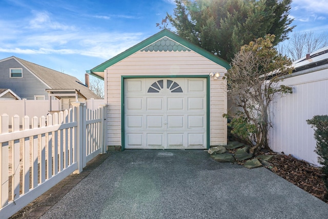 detached garage featuring fence and driveway