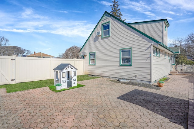 back of house featuring a gate, a patio area, a fenced backyard, and an AC wall unit