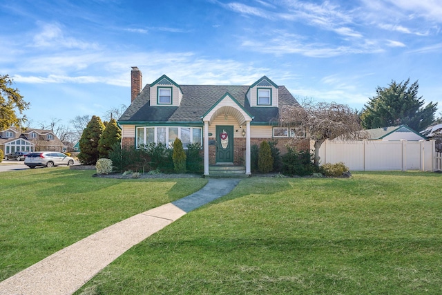 cape cod-style house featuring brick siding, a chimney, a front yard, and fence