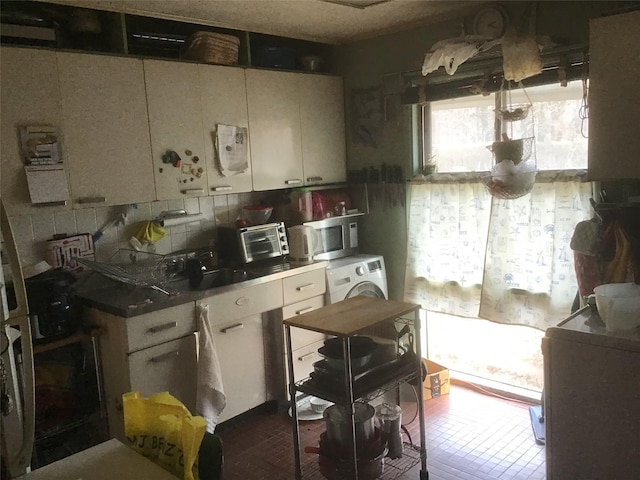 kitchen with a toaster, a sink, backsplash, washer / clothes dryer, and stainless steel microwave