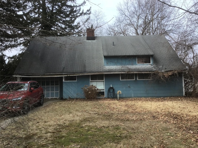 rear view of property with an attached garage and a chimney