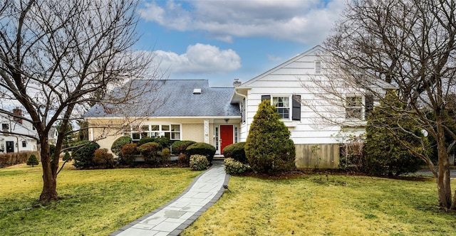 view of front of house featuring a front yard, brick siding, and a chimney