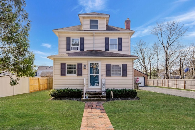 american foursquare style home featuring an outbuilding, a chimney, a front lawn, and fence