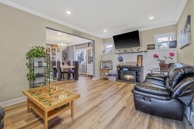 living room with plenty of natural light, a notable chandelier, light wood-style flooring, and crown molding